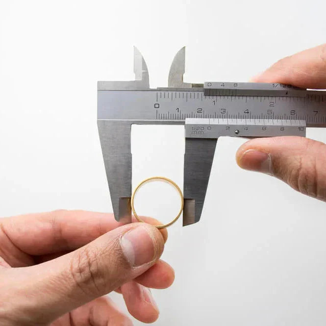Medindo anel dourado com paquímetro metálico para determinar o tamanho do dedo