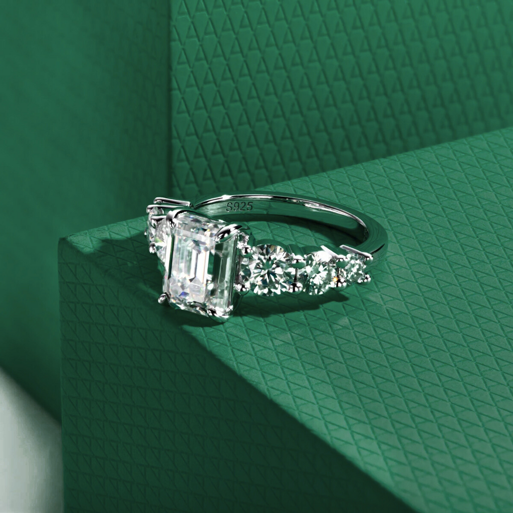 anel de prata 925 com pedra central retangular e moissanites em fundo verde texturizado