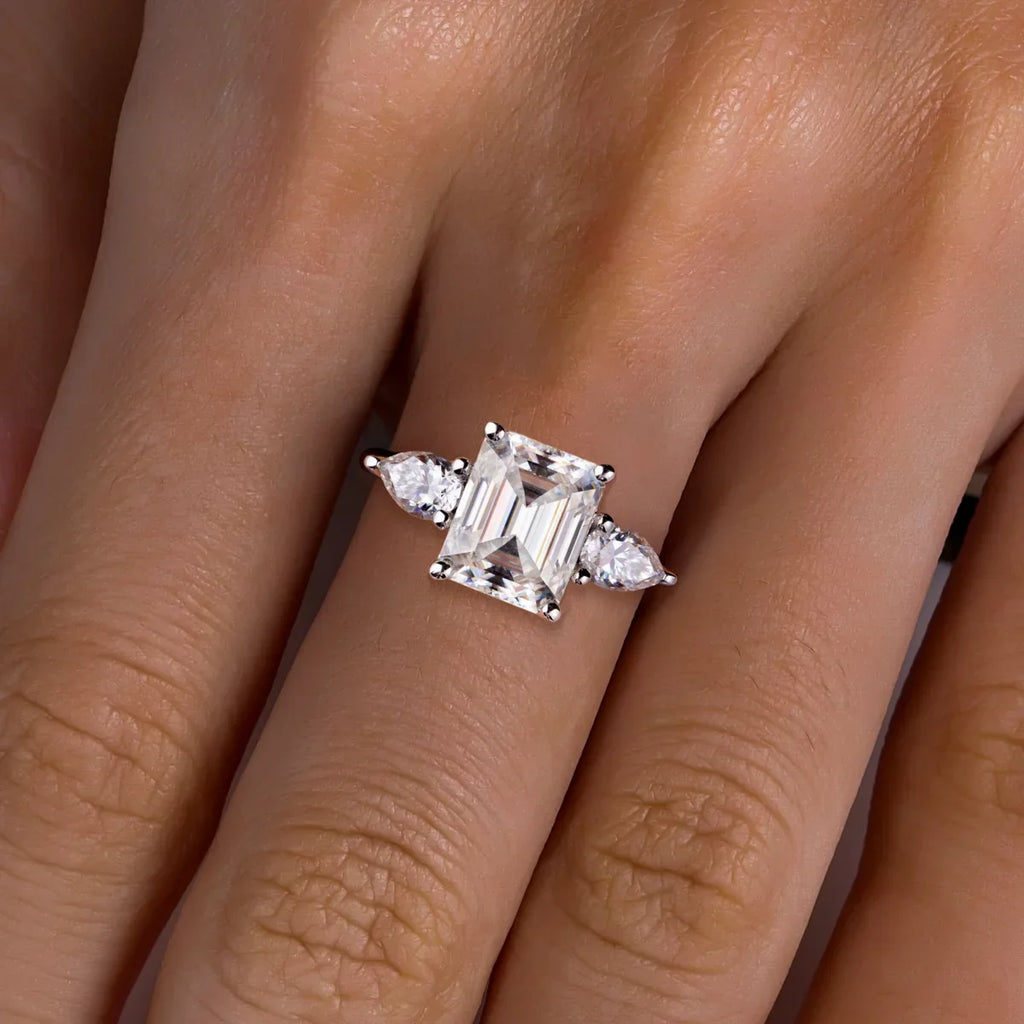 Anel solitário de prata com pedra central quadrada facetada e duas pedras laterais em formato de gota