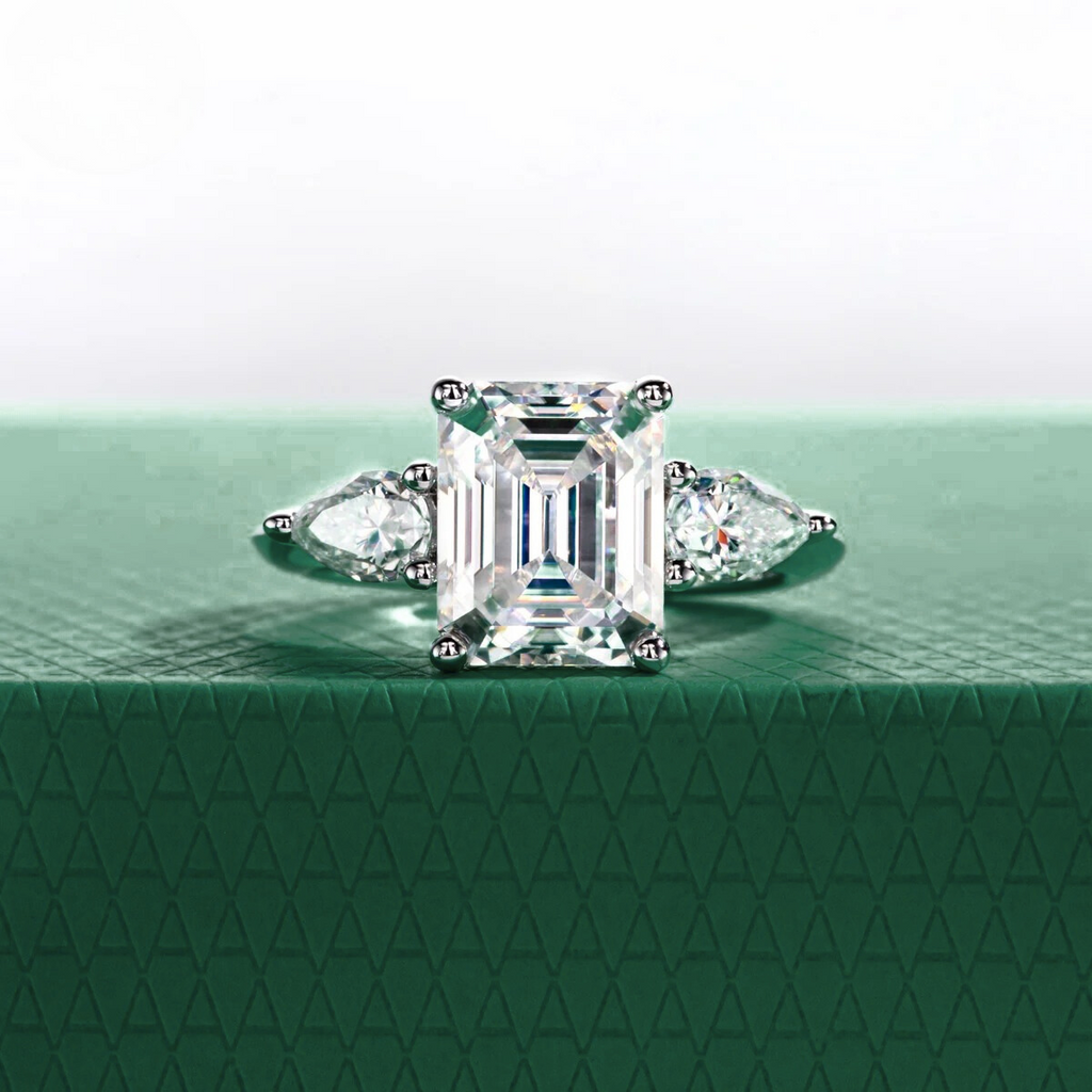 Anel solitário com lapidação esmeralda e moissanite central, pedras laterais em corte pera, base verde texturizada